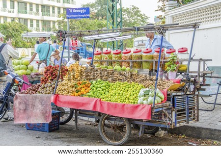PHNOM PENH, CAMBODIA, JANUARY 1, 2013: Seller of fruits, vegetables and sweets displays his merchandise on mobile trailer