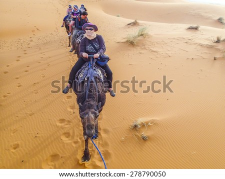 MERZOUGA, MOROCCO, APRIL 13, 2015: Tourists visit Dunes Erg Chebbi near Merzouga during a camel excursion