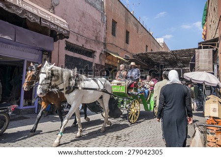 MARRAKESH, MOROCCO, APRIL 16, 2015: Tourists visit old medina traveling by horse drawn carriage