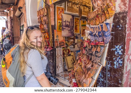 MARRAKESH, MOROCCO, APRIL 16, 2015: Female tourists watches hand made leather shoes displayed in medina