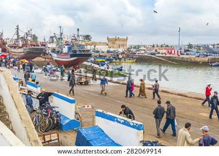 AS-SAWIRA, MOROCCO, APRIL 7, 2015:  Local people and tourists walk in busy fishing port of As-Sawira