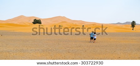 Couple of tourists visiting sand dunes in Merzouga, Morocco