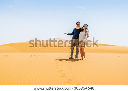 Couple of tourists posing on sand dunes in Merzouga, Morocco