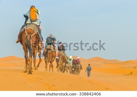 MERZOUGA, MOROCCO, APRIL 13, 2015: Tourists take part in camels trip on sand dunes of Erg Chebbi