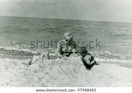 Vintage photo of mother and daughter building sand castle (fifties)