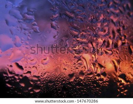 Sunset seen through window covered with raindrops, background