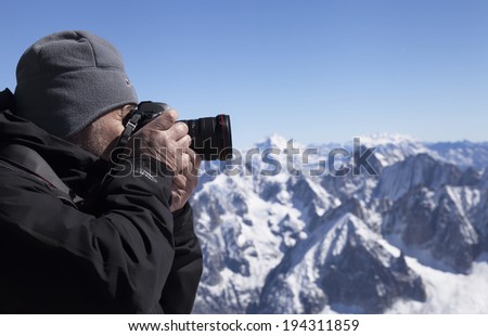 FRENCH ALPS - 14 SEPTEMBER 2012: Mountain walker takes photos of snow covered Alps with Canon 5D Mk II