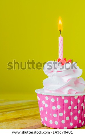 Cupcake with candle on top on color background