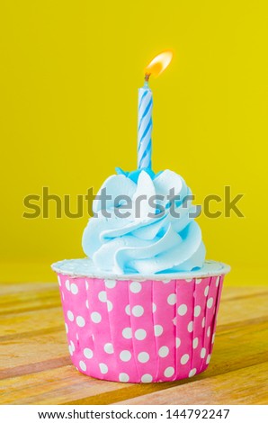 Cupcake with candle on top on color background