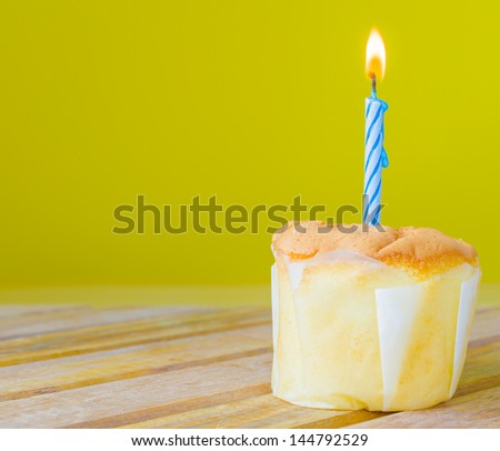 Vanilla cake with a candle on top on yellow background