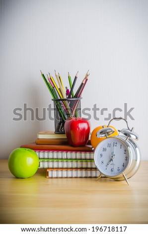 Back to school , note book , clock , pencil , apple on wood table