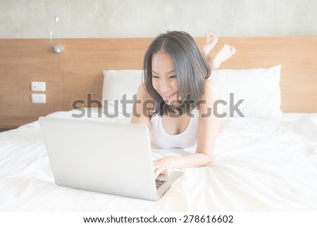 Young asian woman using computer in bedroom - vintage film tone effect and light filter processing
