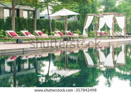 Umbrella and chair deck in hotel resort swimming pool - Filter effect