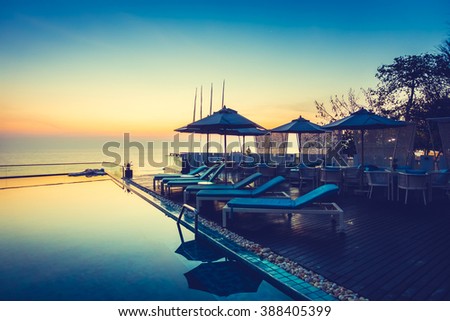 Beautiful luxury swimming pool in hotel resort with silhouette umbrella and chair around pool with sunset and twilight times - Vintage Filter and Boost up color Processing