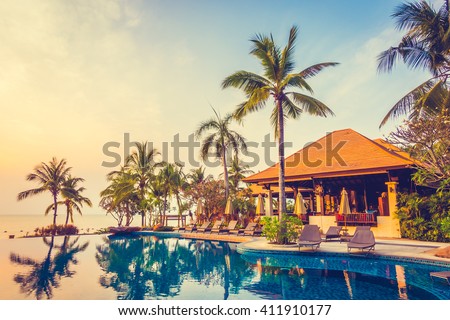 Beautiful luxury Swimming pool with palm tree and sea background in hotel pool resort - Vintage Filter and Boost up color Processing