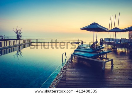 Beautiful luxury swimming pool in hotel resort with silhouette umbrella and chair around pool with sunset and twilight times - Vintage Filter and Boost up color Processing