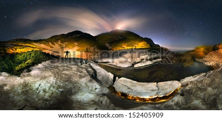 Moon over the top of Pop Ivan Maramorosh and lonely figure, drawing a powerful LED flashlight pictorial compositions of the alpine lake, where icebergs float