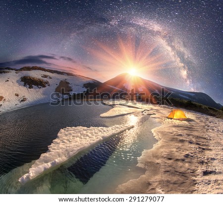 In the spring a group of tourists spend the night in the snow and ice alpine lake Nesamovite Montenegrin ridge of the Carpathians, in the starry sky galaxy at moonrise