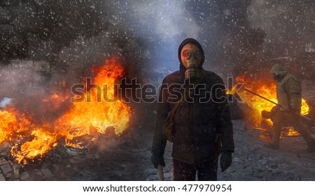 Radical Protestant in the mask represents the protesters against the authorities among the burning of the capital of the European quarter. Burning rubber tires wheel of fire smoke soot street fighting