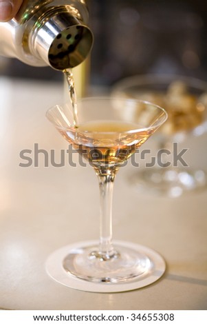 A glass of cocktail pouring from the shaker at a bar
