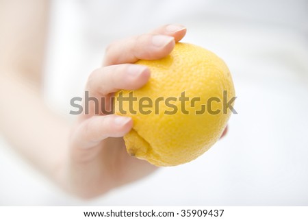 FRUIT IMAGE-a fresh lemon with a woman\'s hand isolated on white