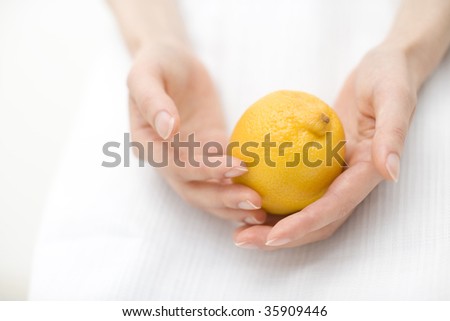 FRUIT IMAGE-a fresh lemon with woman\'s hands isolated on white
