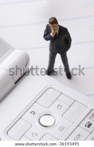 A model of business man looking at white mobile