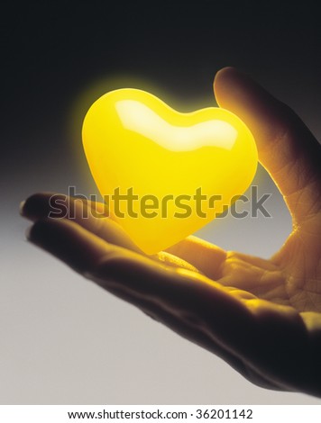 GRAPHIC IMAGE-a yellow heart with a woman\'s hand