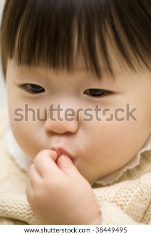 A little girl is pursing her lips with her fingers.