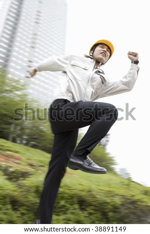 Workman jumping with a high-rise building in the background