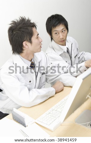Two workmen operating computers side by side