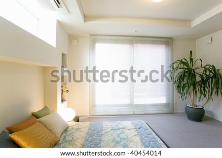 Bedroom with a big window and a plant.