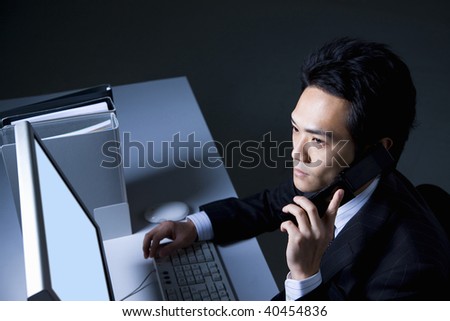 The businessman who calls with a cellular phone to the PC on the desk.