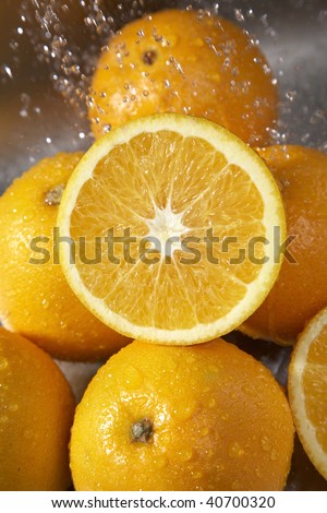 Many oranges washed in the sink in a kitchen.