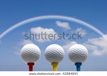 Three tee-up golf balls isolated on the blue sky with rainbow