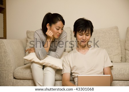 A young couple sitting on the sofa and using PC