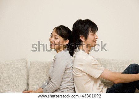 A young couple sitting on the sofa back-to-back
