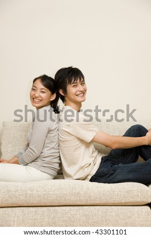 A young couple sitting on the sofa back-to-back