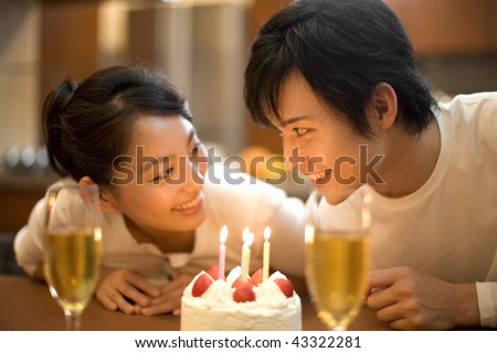 A young couple is smiling with birthday cake and champagne