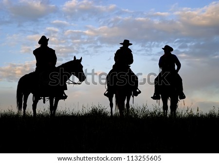 Three cowboys silhouetted against a dawn sky. Montana horse ranch