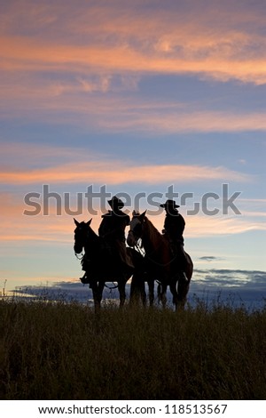 Two cowboys silhouetted against dawn sky,Montana