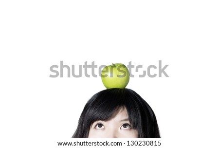 Cropped studio shot of a girl with an green apple resting on top of her head isolated on white