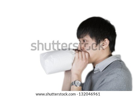 Man holding paper bag over mouth as if having a panic attack or being nauseated