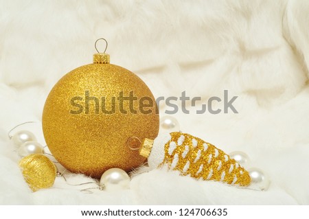 Christmas decorations in gold and white colors: cones and balls on a white fur closeup