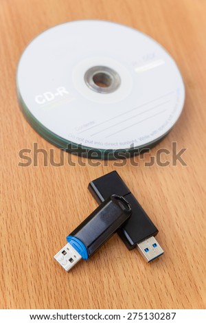 USB flash drives and stacked CDs isolate on wooden background.