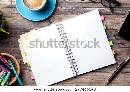 Office table with a coffee cup, a blank notepad and a plant