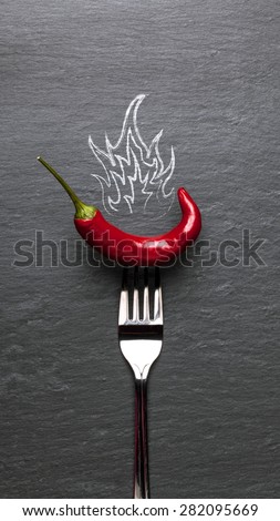 red chili pepper with fire and a black graphite background