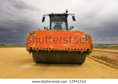 Road roller at worksite and cloudy sky