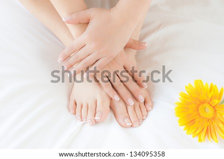 Woman\'s hands and feet after beauty treatment, showing off her manicured finger nails and pedicured toe nails.