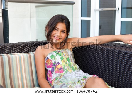 Beautiful young girl poses on a patio chair at a luxury hotel